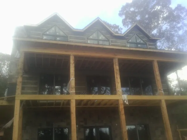Dormers and porch framing on a large log home under construction — Roof Coating work by our crew in Coal Valley
