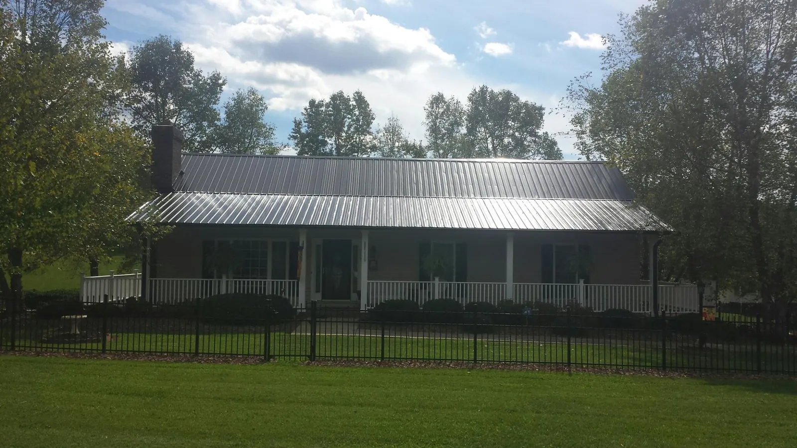 Gray metal roof on a brick ranch with a full width front porch — Gutter Guard Installation work by our crew in Coal Valley