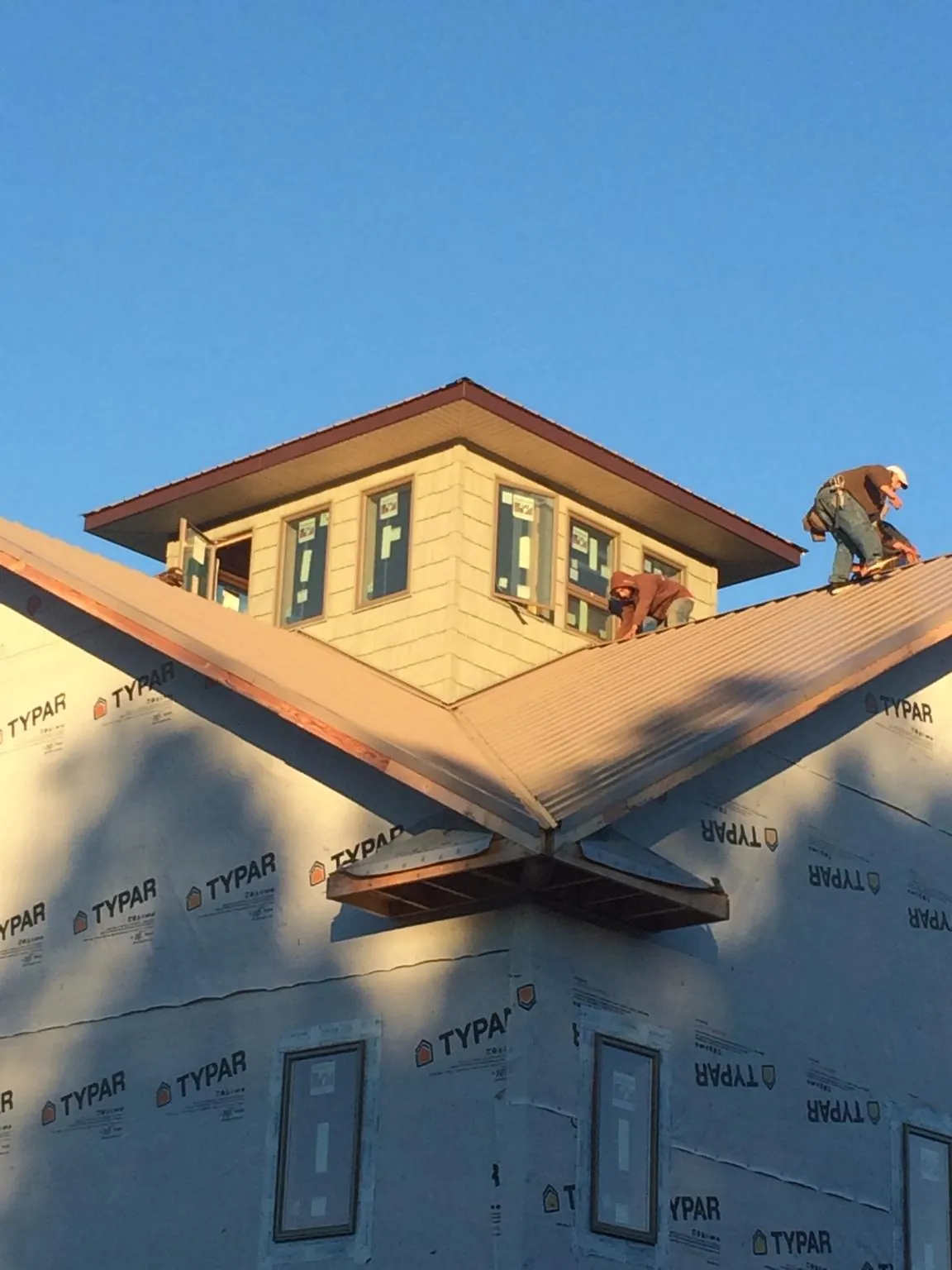Roofers working around a rooftop cupola on a new metal roof at sunset — Roof Waterproofing in Coal Valley by Roofing Brothers